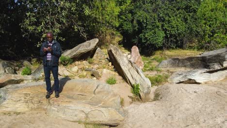 African-black-man-drone-pilot-flying-in-the-rural-savanna-of-Kenya