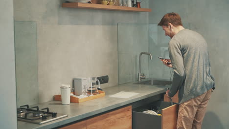 young man having a video call with a smartphone while having breakfast in the kitchen