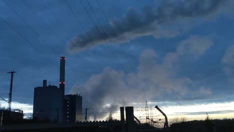 Power-plant-in-industrial-area-in-front-of-blue-dusk-sky-producing-a-huge-vapor-cloud