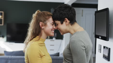 Happy-caucasian-lesbian-couple-embracing,-smiling-and-laughing-in-sunny-kitchen