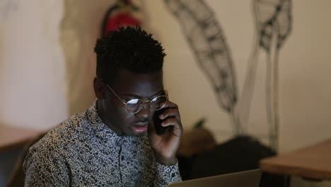 focused freelancer using laptop and talking by smartphone