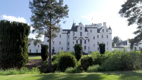 right to left low track of blair castle on a sunny day with flare between the trees