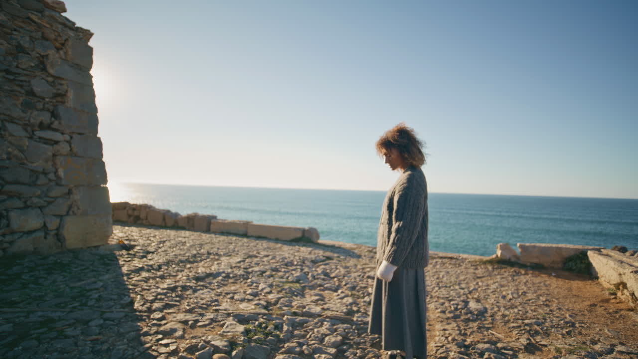 Lonely girl walking marine hill at evening. Serene woman looking rocks relaxing