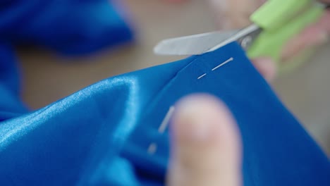 tailor cutting blue textile in close up