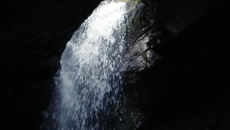 water falling through a hole into a cave at donut falls in big cottonwood canyon, utah