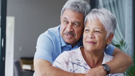 Happy-senior-biracial-couple-talking-and-embracing