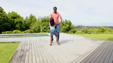 african american, father and daughter dancing joyfully on wooden deck in sunny backyard