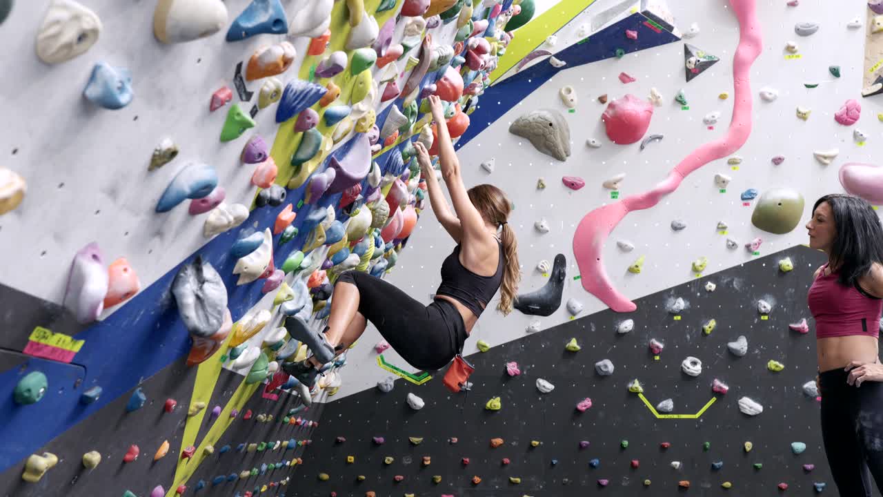 여자 들 이 다채로운 손잡이 를 가지고 바위 벽 을 오르고 있다