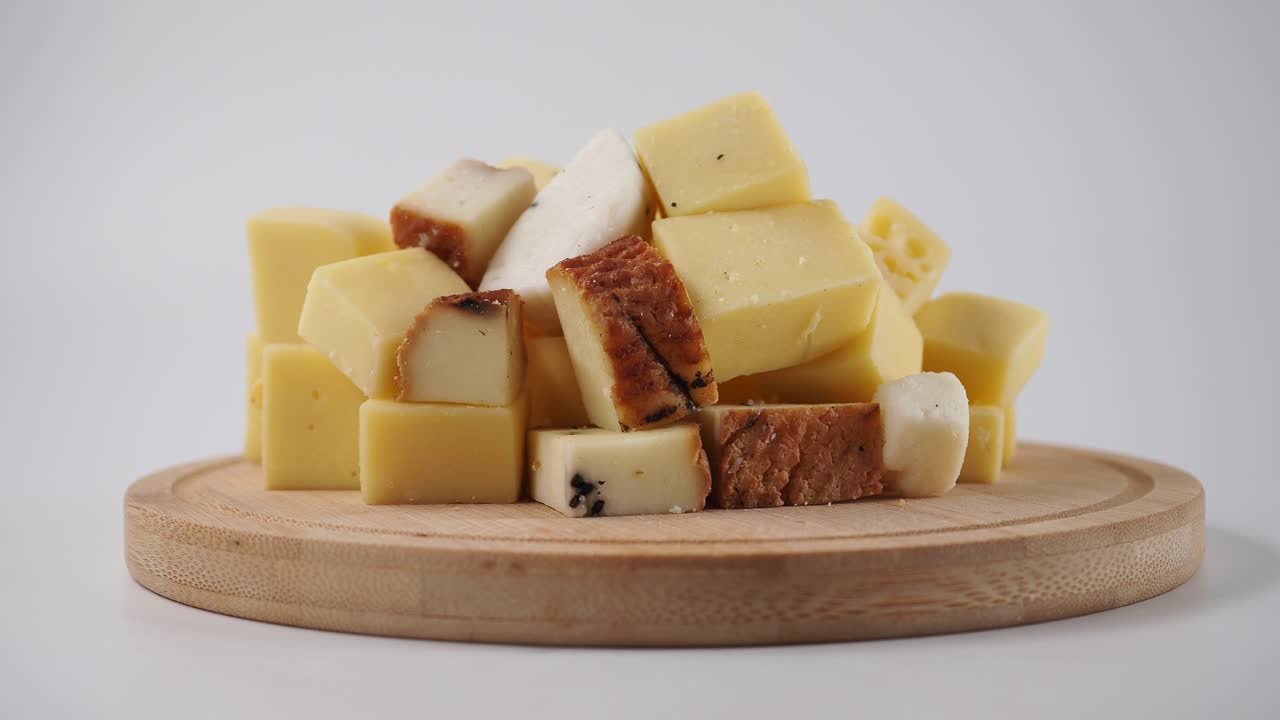 Assortimento di cubetti di formaggio su tagliere di legno