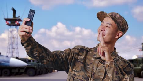 close up of asian man soldier using smartphone taking picture while standing at military camp