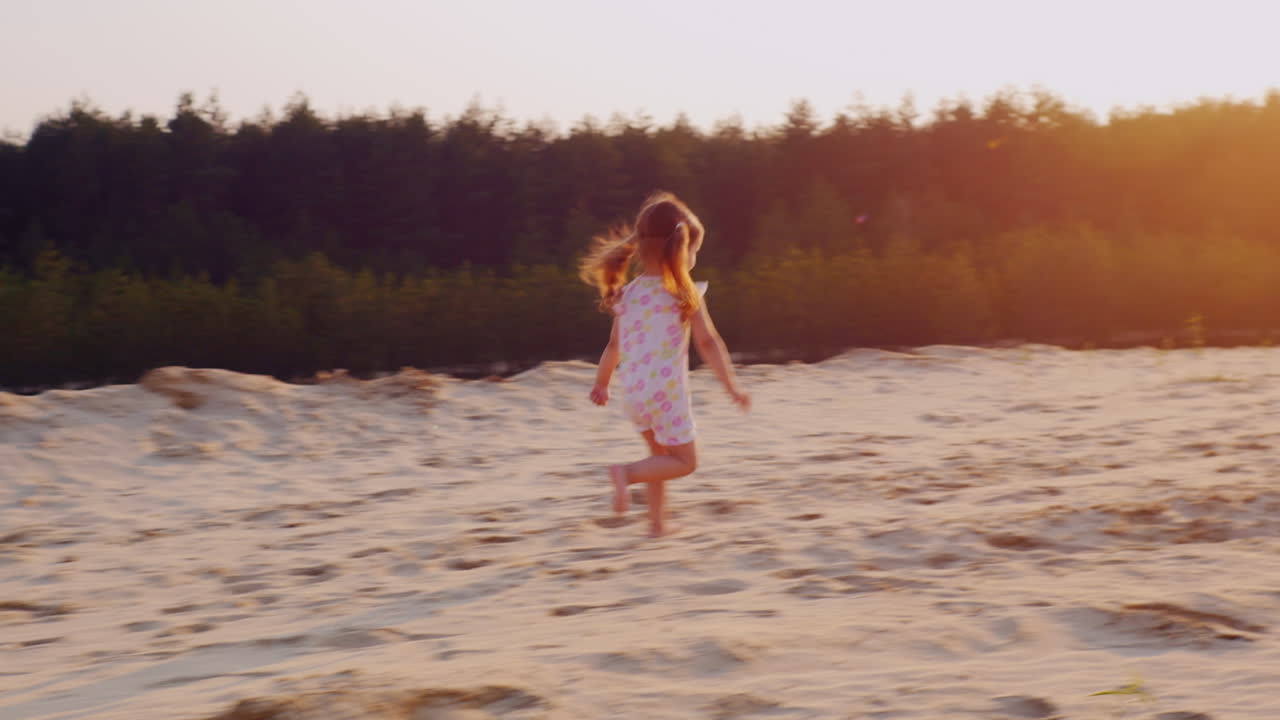 해변을 배경으로 석양을 향해 모래사장을 달리는 3년 근심 없는 소녀