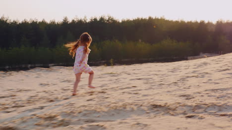 carefree girl 3 years running through the sand toward the setting sun against the background of the