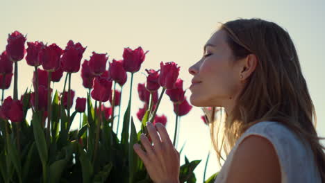 Closeup-female-touching-flower-bud.-Smiling-girl-enjoying-tulip-in-sun-beams.