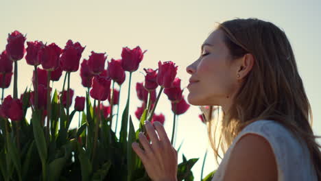 closeup female touching flower bud. smiling girl enjoying tulip in sun beams.