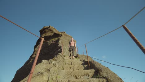 Woman-hiking-alone-down-rock-steps-of-mountain-ridge-trail,-Pico-do-Arieiro