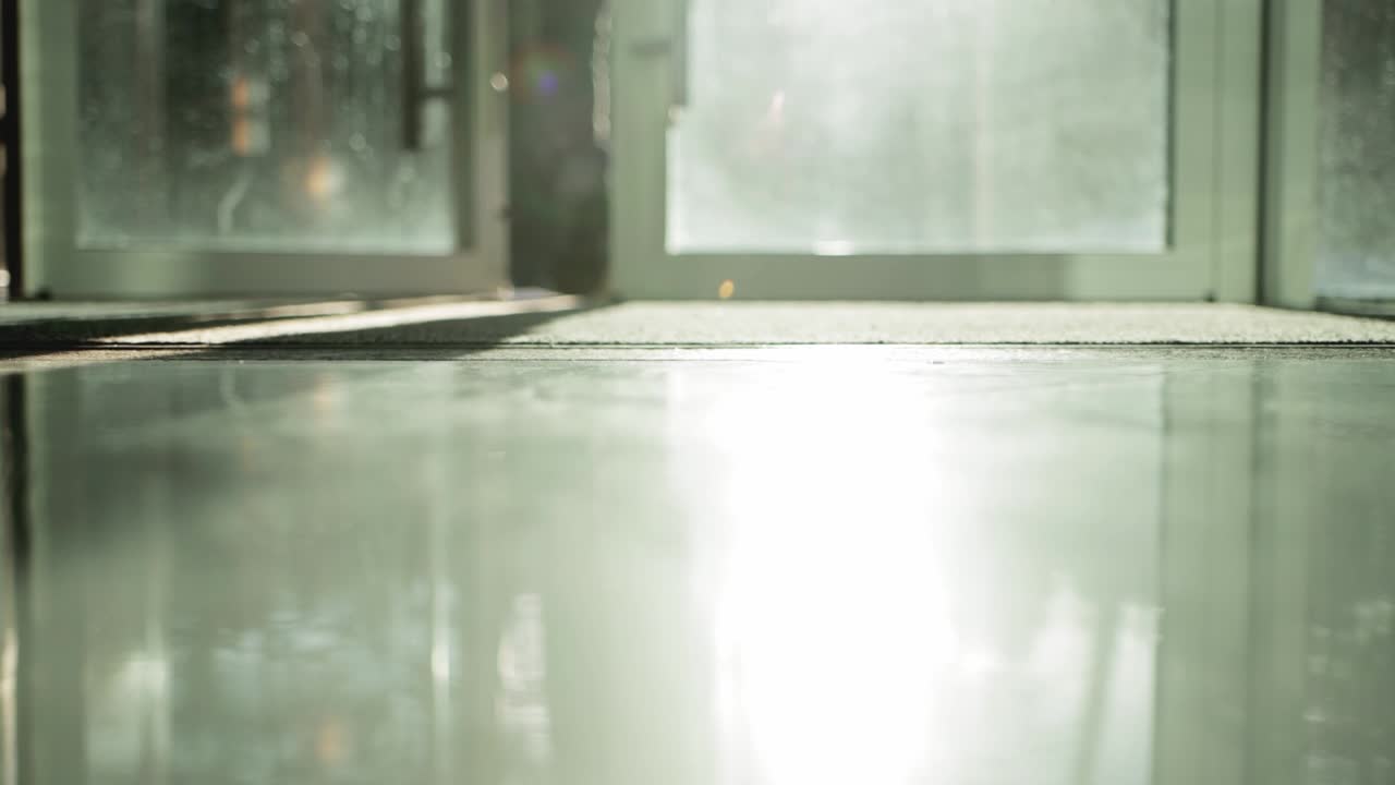 한 남자가 유리 자동 문과 빛이 비치는 방에서 밖으로 나갑니다.