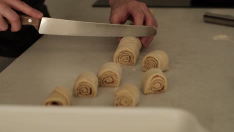 white male chef cuntting homemade cinammon rolls on kitchen countertop