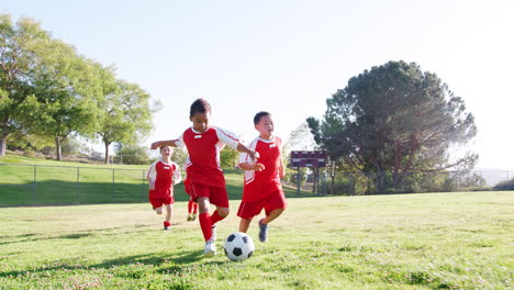 group of young boys in soccer team kicking ball shot in slow motion