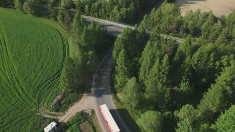 aerial view of a bridge in the countryside with a truck passing underneath and cars driving over the bridge