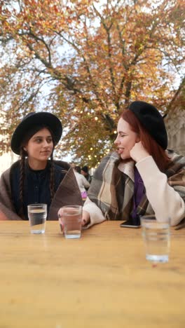 two friends enjoying an outdoor cafe in autumn