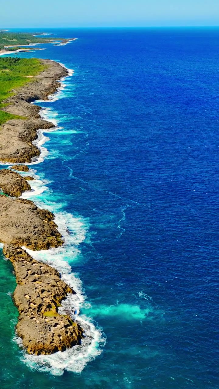 Costa atlantica con surf a Mar Chiquita, Manati, Porto Rico. Ripresa aerea di onde che si infrangono contro rocce vulcaniche frastagliate e una barriera corallina poco profonda. Video verticale
