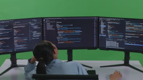 back view of bored asian woman developer write code with multiple computer screens in green screen studio