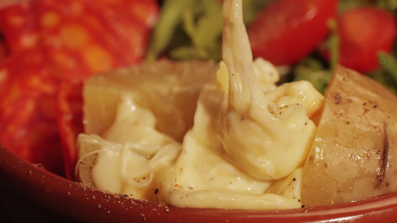 Traditional Swiss melted raclette cheese, hot melted French dish, family cooking dinner with Spanish style tapas ingredients and grill.