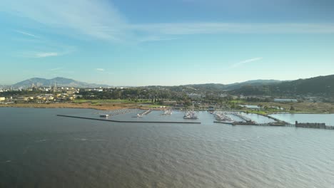 aerial drone panoramic tracking left of carquinez strait shoreline, featuring wetlands, harbor, and rolling hills in california
