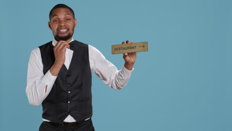 Doorman-bellhop-showing-the-restaurant-direction-with-a-hotel-sign