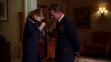 a young girl helps a soldier with his uniform