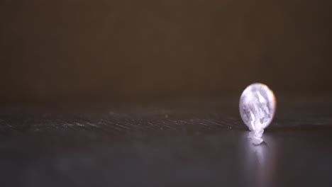 a penny spins in slow motion across a black wood table