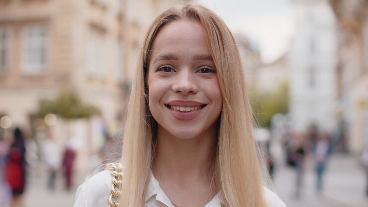 Una giovane donna felice sorridendo guardando via sognando riposando buone notizie sentendosi soddisfatta per la strada della città