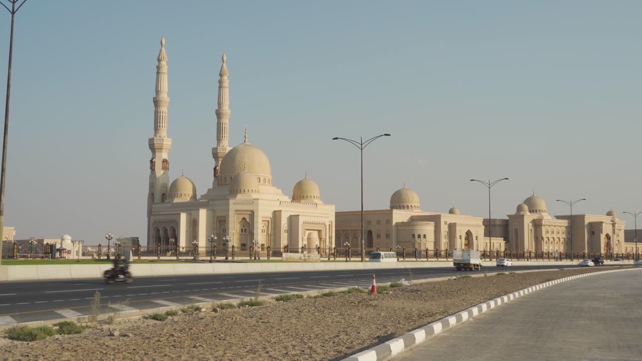 exterior de la mezquita de la universidad al qasimia contra el cielo azul a lo largo de la vía urbana en sharjah, emiratos árabes unidos