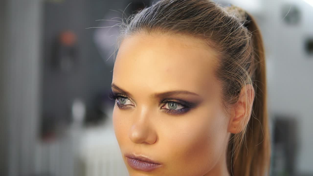 toma de cerca de los sprays del peluquero spray para el cabello en un modelo mientras hace el peinado. el peluquero hace el peinado para el modelo de cerca