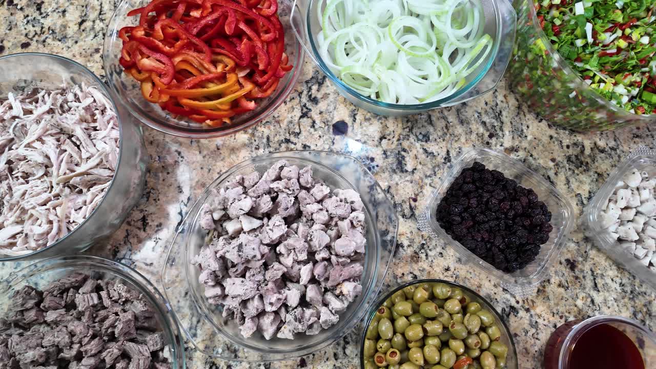 Ingredientes visíveis de cima para baixo, como carnes moídas, pimentões, cebolas, azeitonas e passas, são típicos deste prato de Natal. Processo de preparo trabalhoso