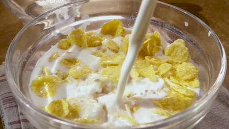 crispy yellow corn flakes into the bowl for the morning a delicious breakfast with milk. slow motion with rotation tracking shot.