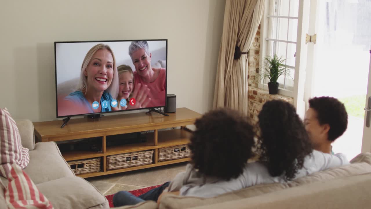 Famiglia afroamericana che fa una videochiamata in TV mentre è seduta sul divano a casa