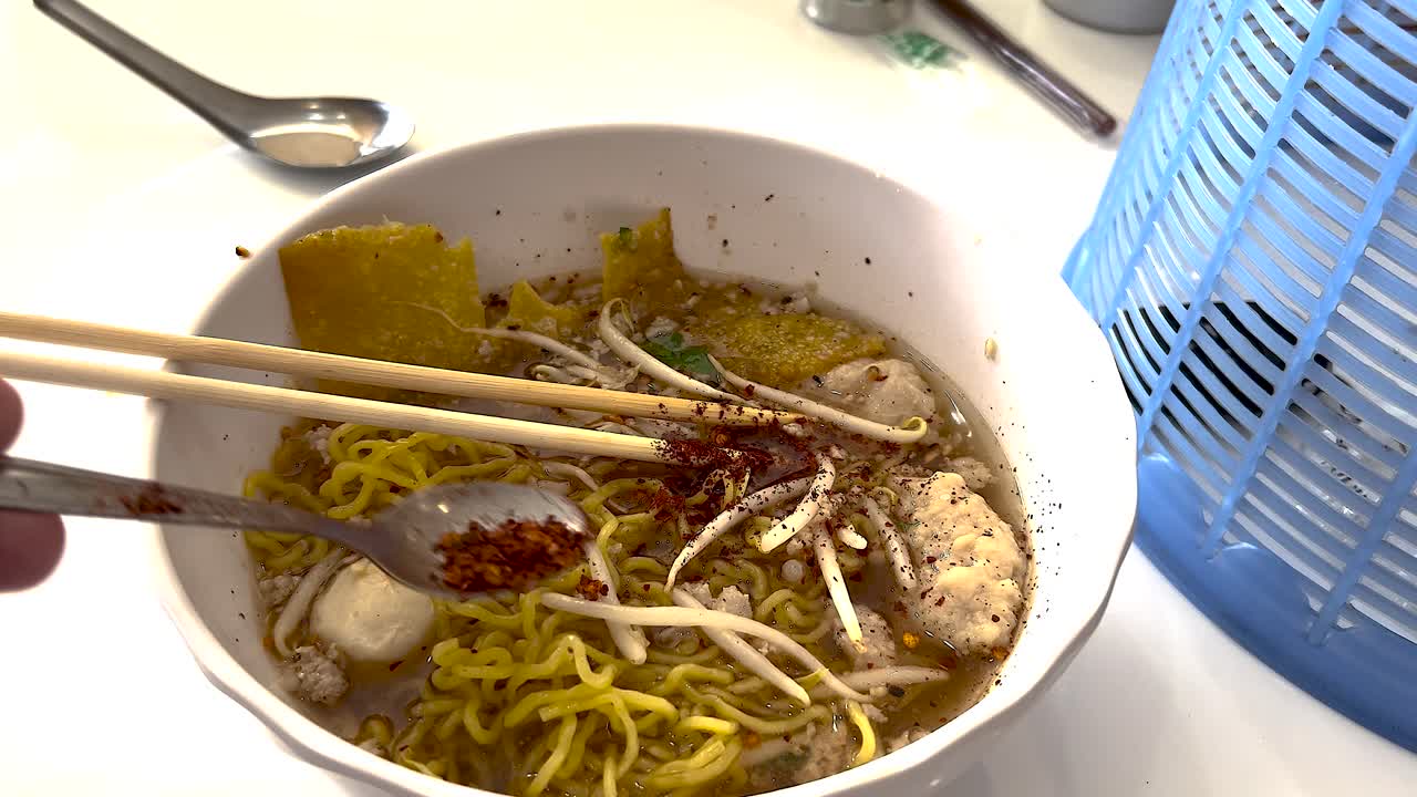 añadiendo especias a un plato de fideos tailandeses