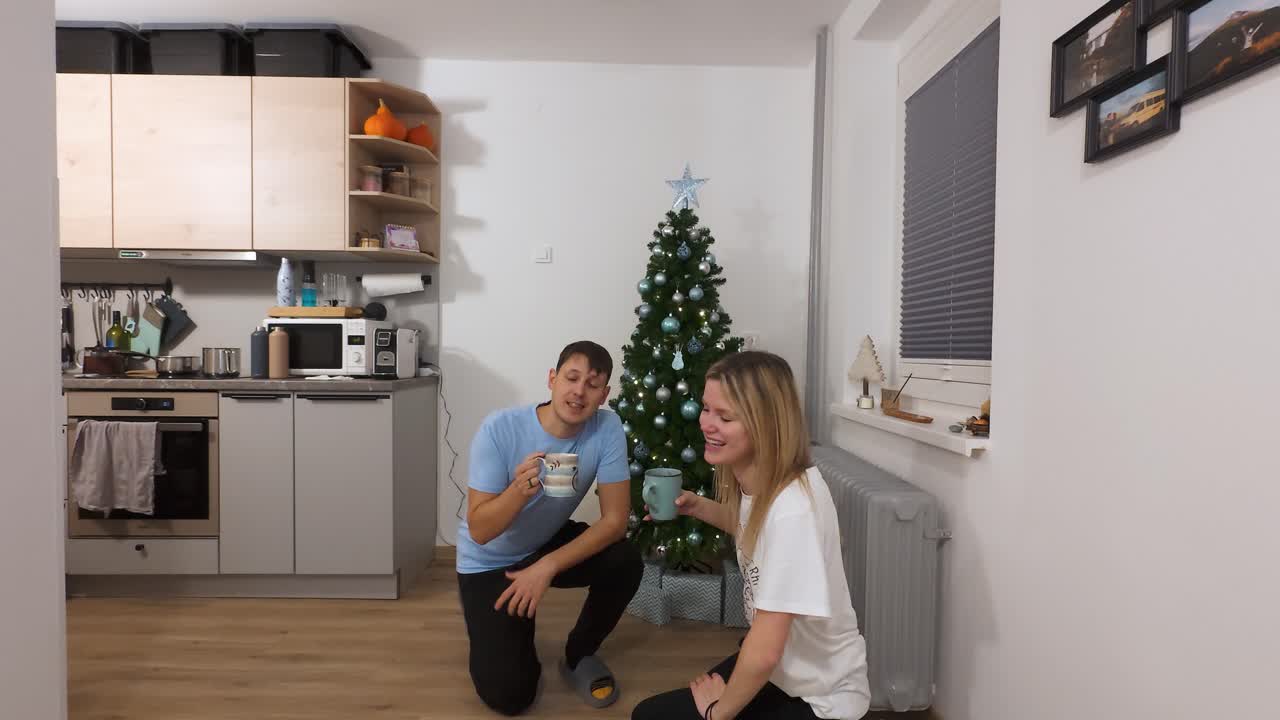 Evde Noel ağacı süslerken sıcak şarap yudumlayan çift, canlı yayın, statik tripod çekimi