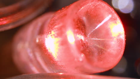 una pequeña bombilla brilla con color rojo en una guirnalda eléctrica