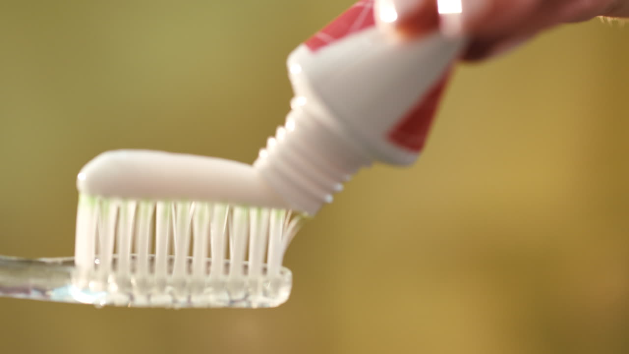 Close up squeezing white toothpaste on toothbrush. Morning teeth hygiene