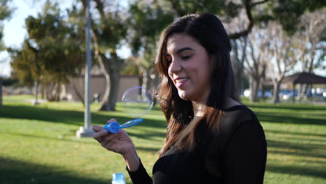 attractive young woman blowing bubbles and laughing with joy and happiness as she has fun playing in the sunlight