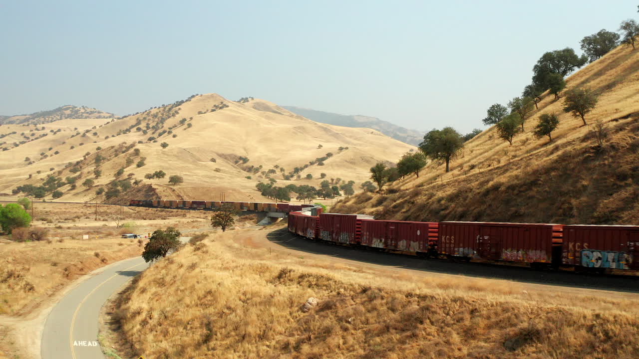 A Union Pacific freight train rolls along the tracks transporting cargo through southern California - aerial view
