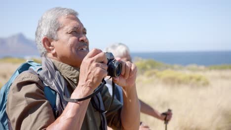 feliz pareja biracial senior en las montañas tomando fotos en un día soleado, en cámara lenta