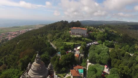 aerial dolly forwards towards viana do castelo church in portugal on forested hilltop