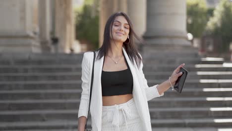 atractiva joven bailando en la calle complacida consigo misma usando un traje de negocios