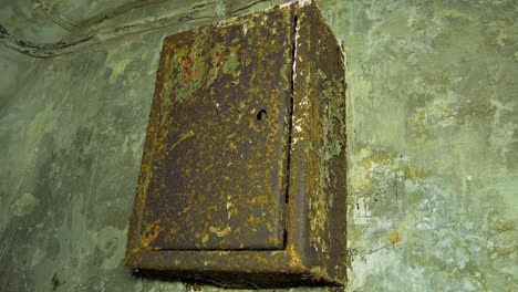 old rusty electrical fuse box inside the concrete bomb shelter to hide civil people, an underground apocalypse bunker built in old coastal fortification, medium handheld closeup shot