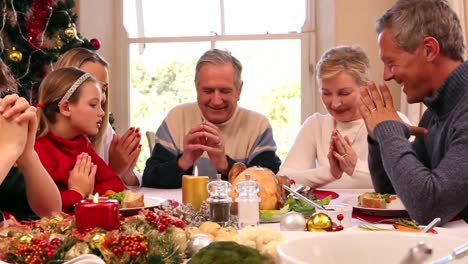 Drei-Generationen-Familie,-Die-Gemeinsam-Vor-Dem-Weihnachtsessen-Gnade-Sagt