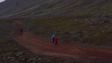 Tourists-enjoingy-the-stunning-countryside-of-Iceland-walking-through-surreal-landscape.-Trekking-visitors-exploring-icelandic-national-park.-Aerial-view-with-slow-camera-rotation