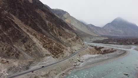 Aerial-drone-forward-moving-shot-of-winding-KKH-road-over-picturesque-Karimabad-Hunza-Valley-with-Rakaposhi-mountains-in-the-background-in-Hunza,-Balochistan